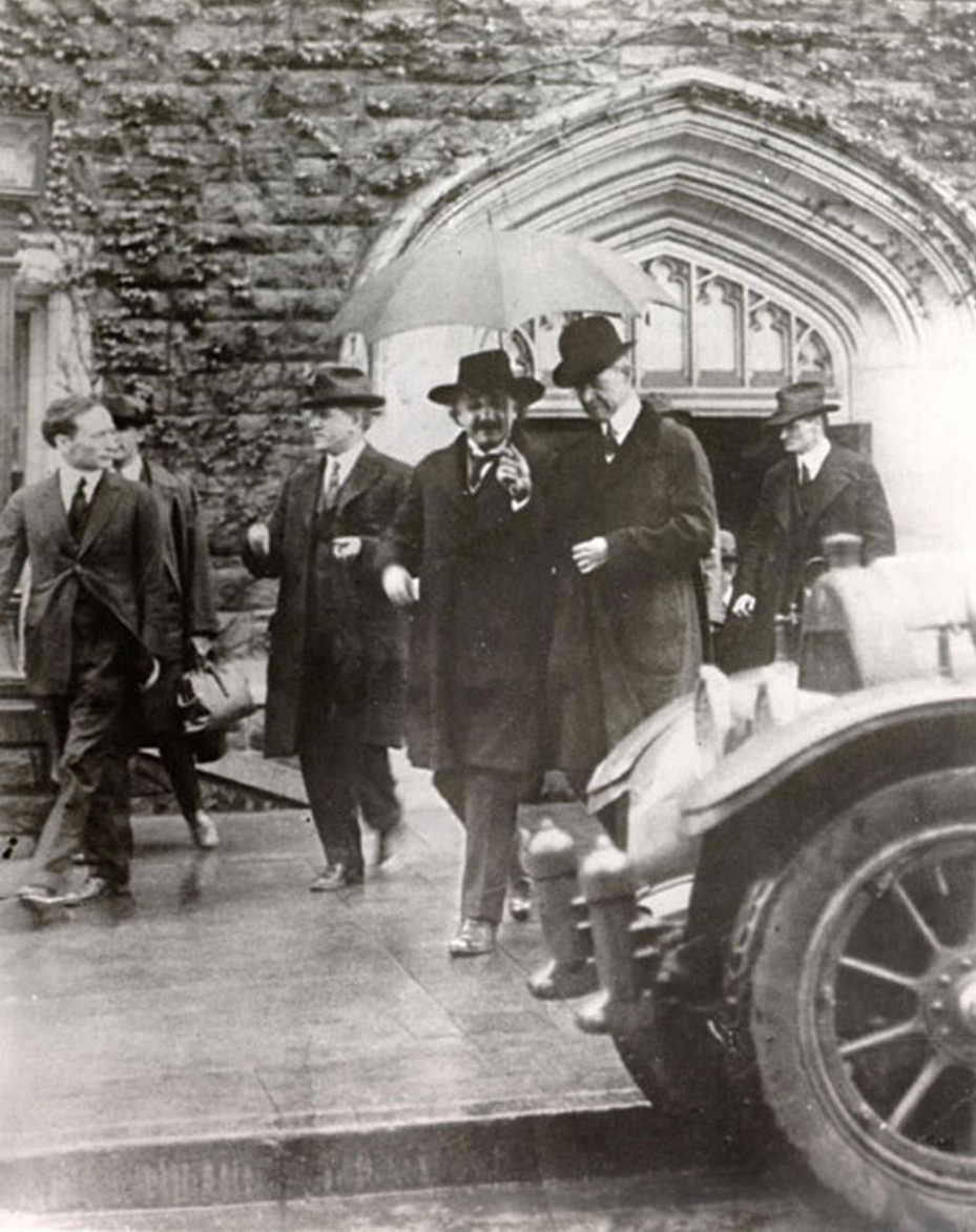 Einstein leaving Shepard Hall under an umbrella held by City College President Mezes. Dr. Rheinhard A. Wetzel is to their left and on the far left is Dr. Morris Cohen.
